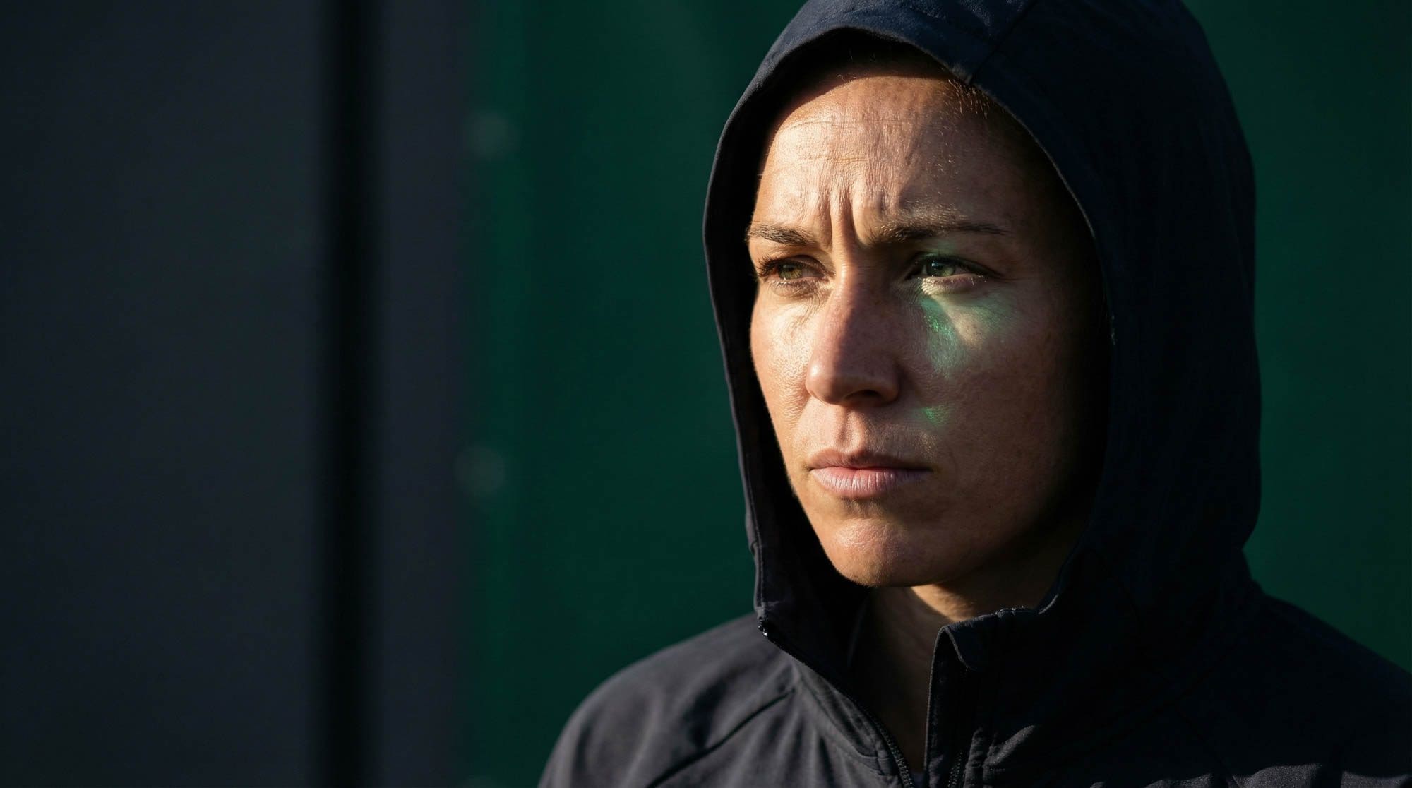 Female athlete in a hooded jacket, focused, in low light