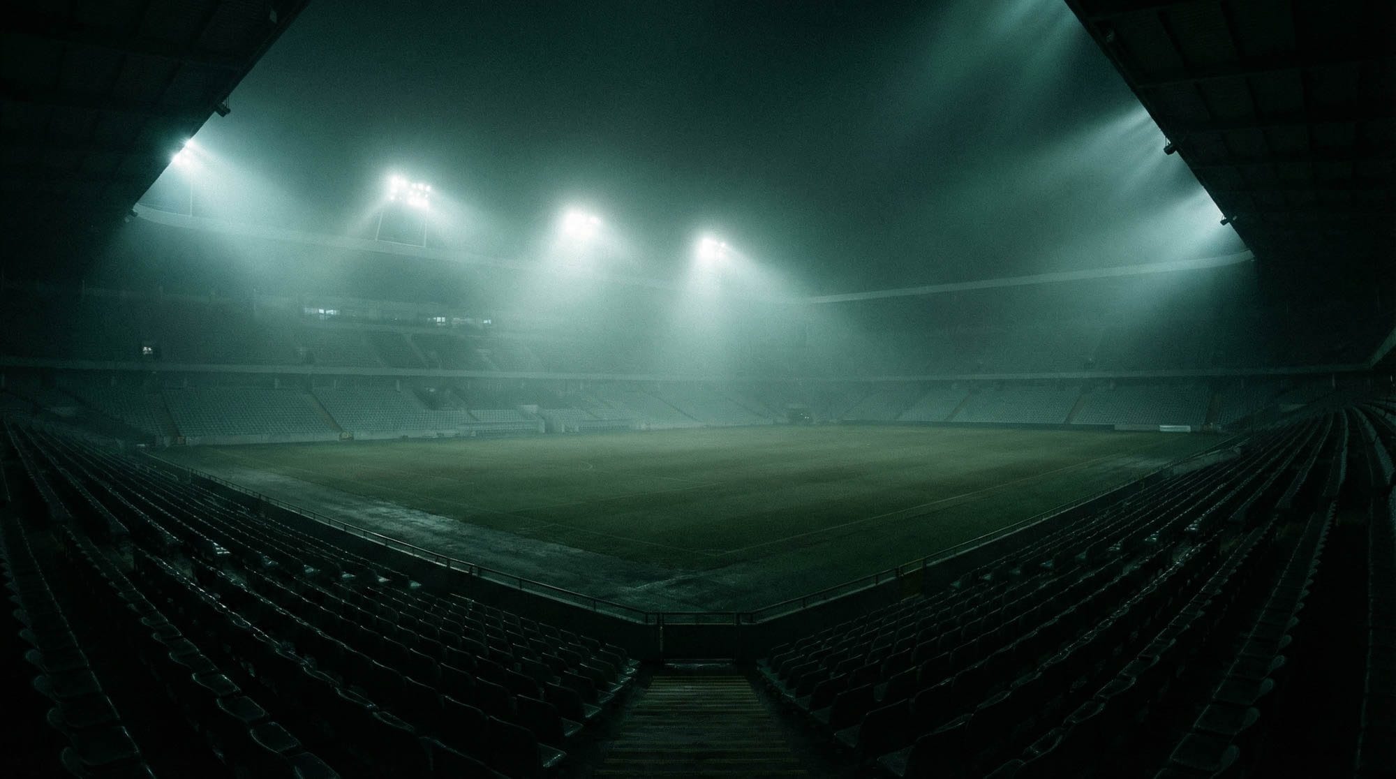 Stadium floodlights cutting through evening haze